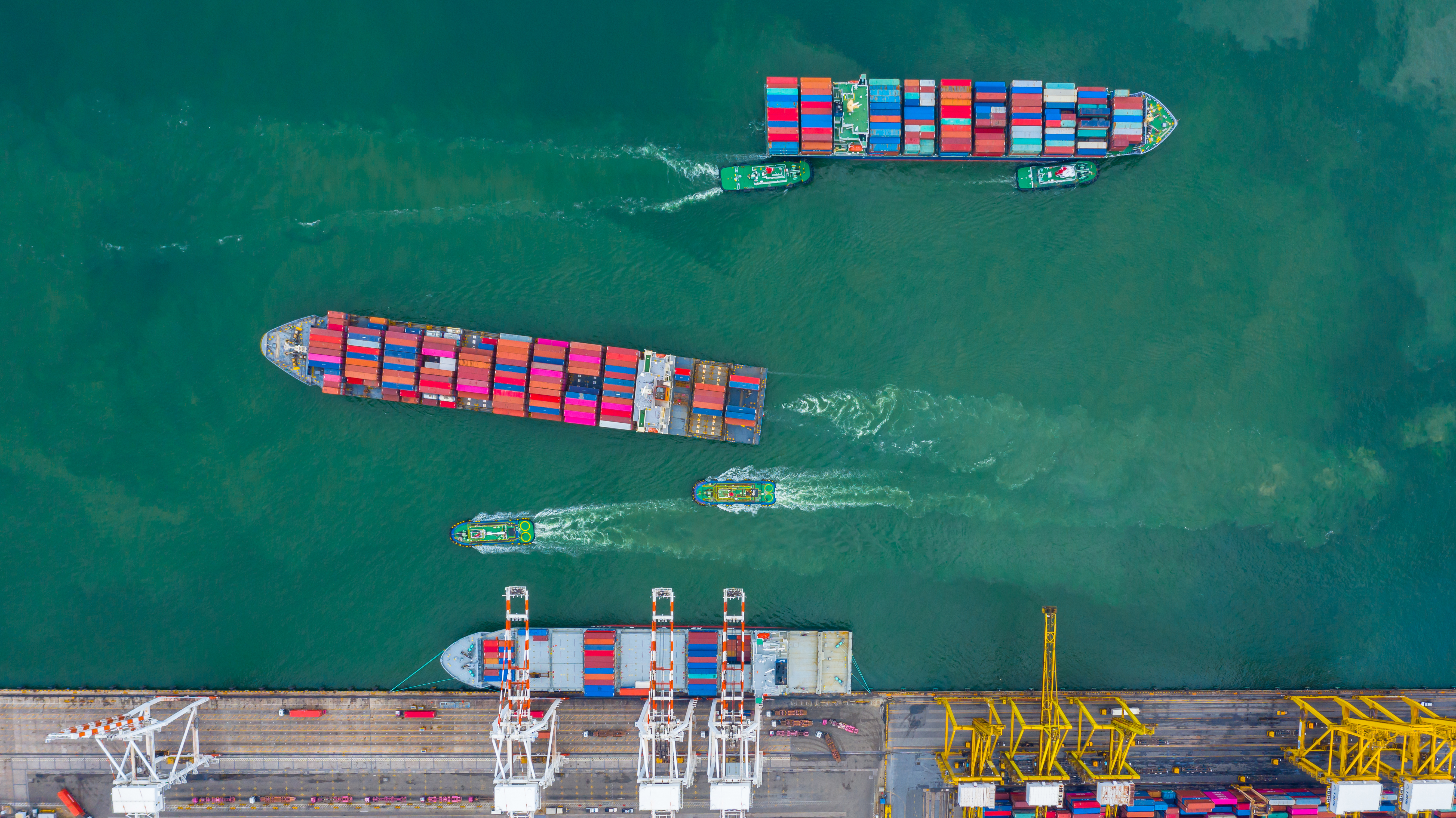 Aerial view cargo ship terminal Unloading crane of cargo ship terminal Aerial view industrial port with containers and container ship 1166335171 5350x3006